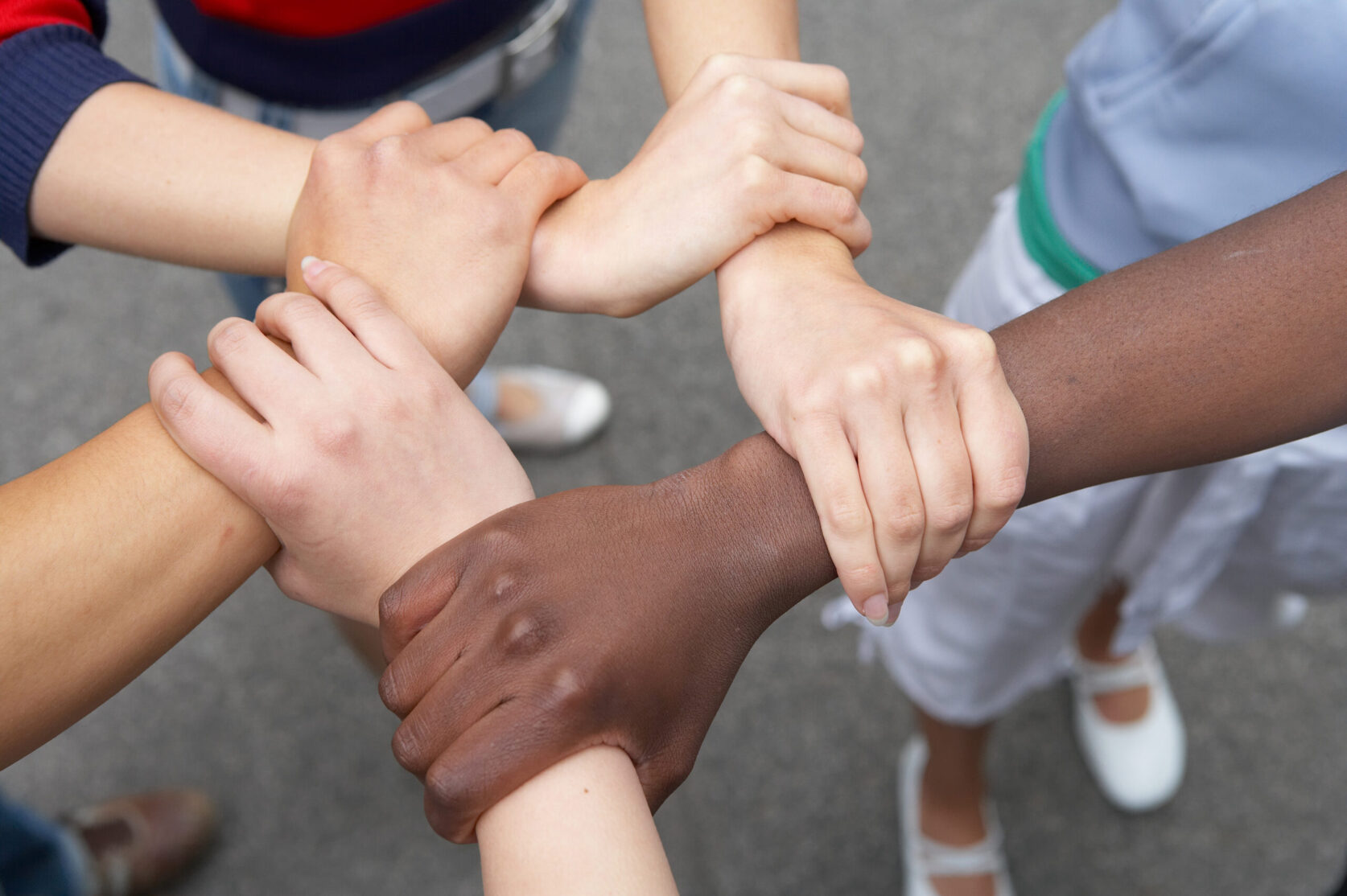 5 Hände internationaler Herkunft halten sich gegenseitig
