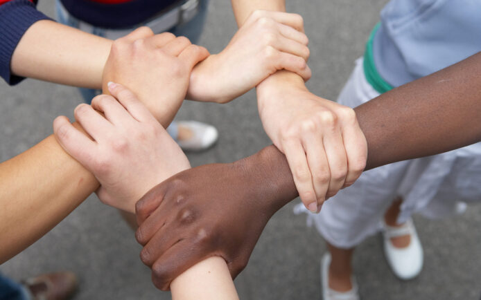 5 Hände internationaler Herkunft halten sich gegenseitig