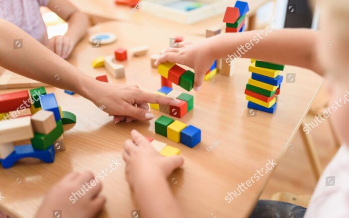 beispiel-stock-photo-preschool-teacher-with-children-playing-with-colorful-wooden-didactic-toys-at-kindergarten-close-1187719603